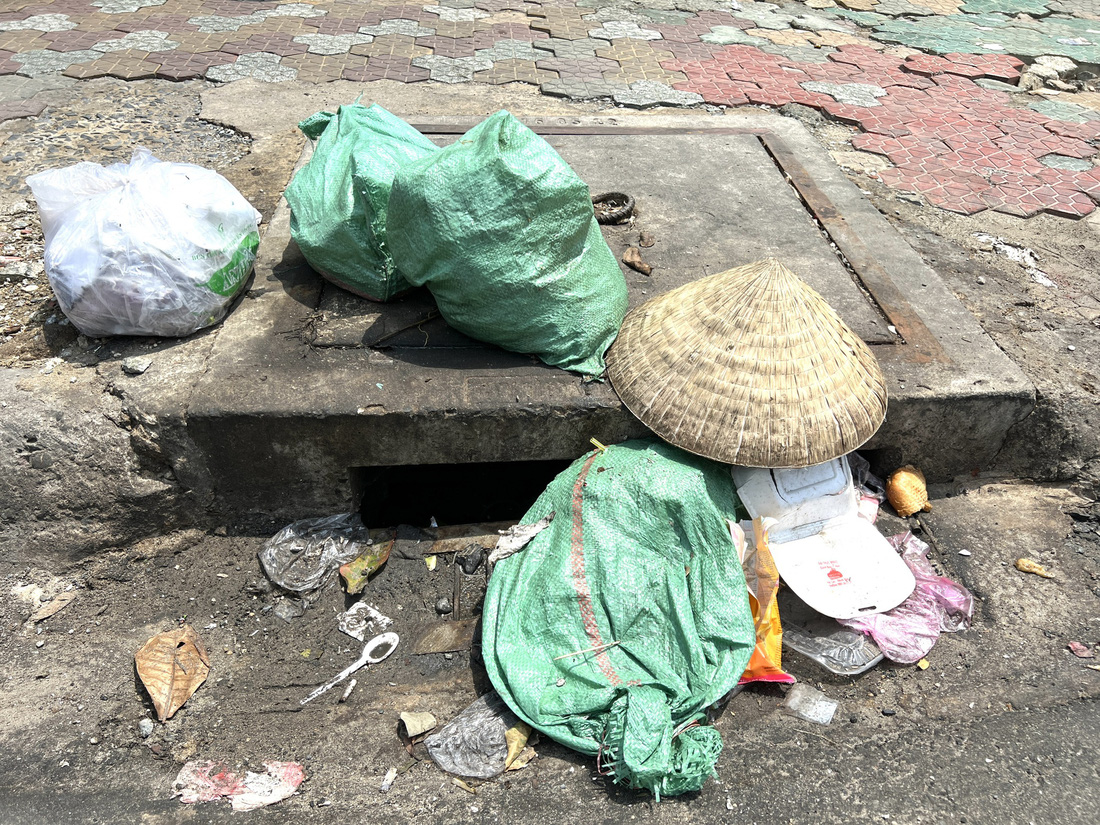Người dân bỏ rác ngay miệng cống trên đường Nguyễn Văn Lượng, quận Gò Vấp - Ảnh: XUÂN ĐOÀN