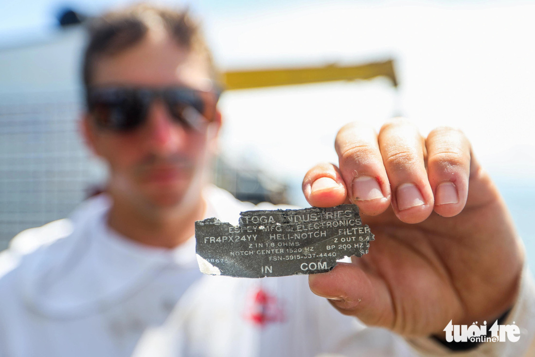 Đại uý Weston Iannone, đội trưởng đội tìm kiếm, cầm một mảnh vỡ từ chiếc máy bay CH-47B được trục vớt từ đáy biển - Ảnh: NGUYỄN KHÁNH