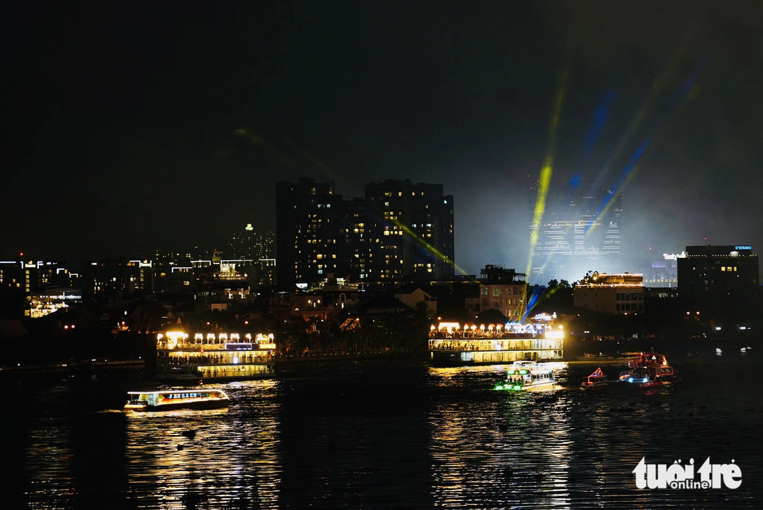 Đoàn diễu hành thuyền như những chiếc đèn lồng thắp sáng con sông Sài Gòn. Những chiếc thuyền du lịch lữ hành chiếu đèn xuyên qua màn khói từ pháo hoa tầm thấp - Ảnh: THANH HIỆP