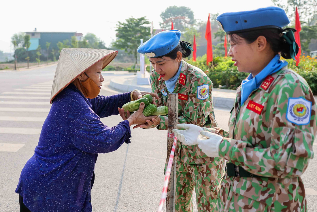 Bà Nguyễn Thị Tơ, một người dân địa phương, tặng dưa chuột cho các cô gái thuộc khối lực lượng Gìn giữ hòa bình, tất cả dưa chuột đều được bà Tơ tuyển chọn và ngâm nước muối sát trùng kỹ càng, nhằm đảm bảo sức khỏe cho các chiến sĩ - Ảnh: NGUYỄN KHÁNH