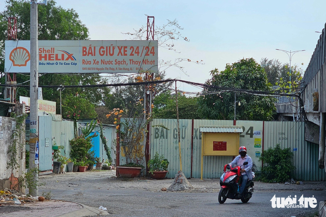 Bãi giữ xe 24/24 nằm trên đường Nguyễn Thị Thập, dưới dạ cầu Him Lam, hiện vẫn có ô tô đậu và ra vào bãi - Ảnh: ÁI NHÂN