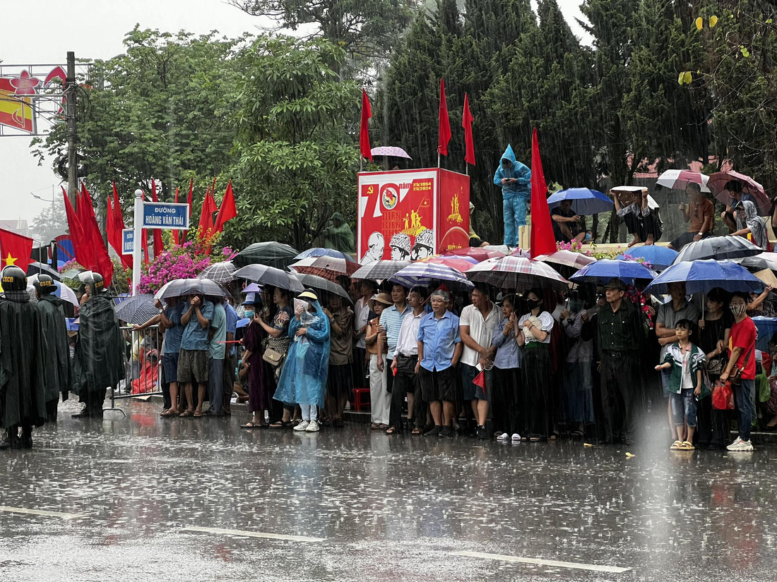 Người dân đội mưa chờ đoàn diễu binh, diễu hành đi qua - Ảnh: NAM TRẦN