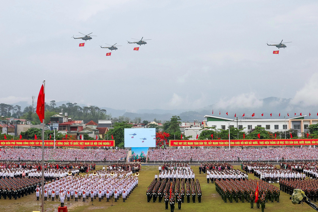 Biên đội trực thăng vũ trang thuộc Quân chủng Phòng không - Không quân, Quân đội nhân dân Việt Nam mang theo cờ Đảng, cờ Tổ quốc bay ngang qua sân vận động tỉnh Điện Biên - Ảnh: NGUYỄN KHÁNH