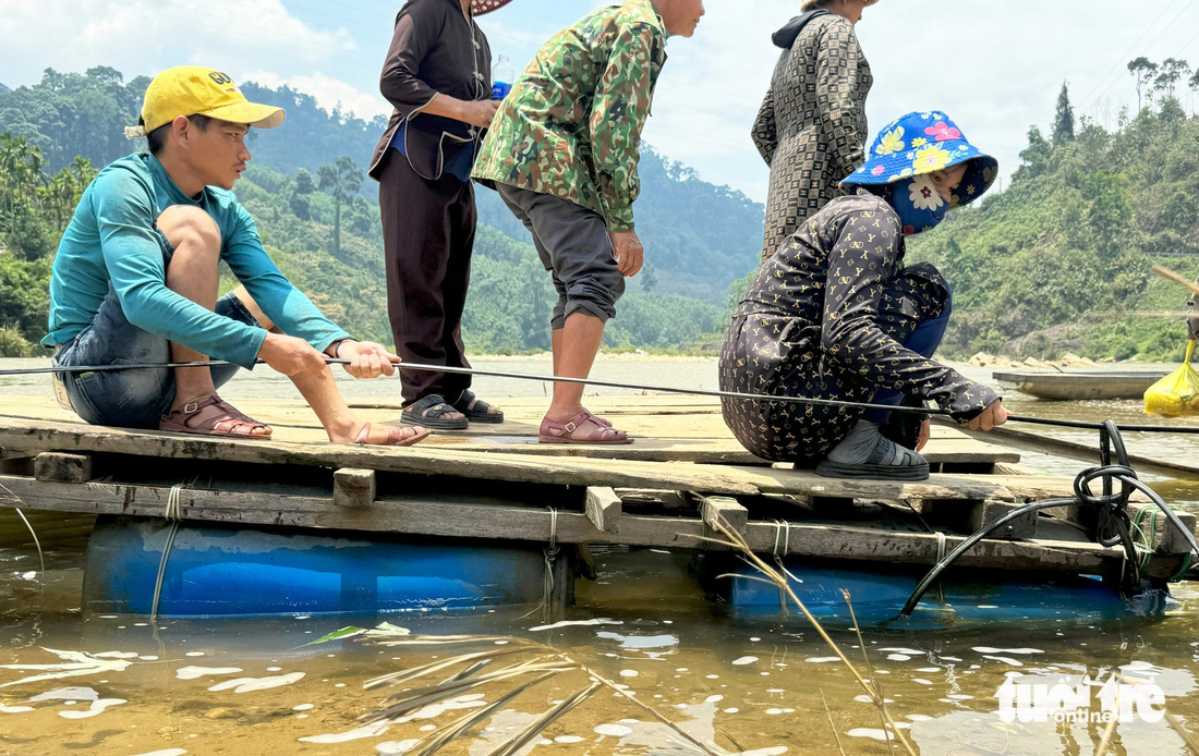 Người dân dùng tay kéo dây cáp để chiếc bè di chuyển trên mặt nước - Ảnh: LÊ TRUNG