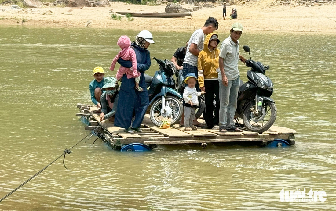 Gần mười người, trong đó có trẻ nhỏ, không ai mặc áo phao ở trên bè tự chế vượt sông Tranh - Ảnh: LÊ TRUNG