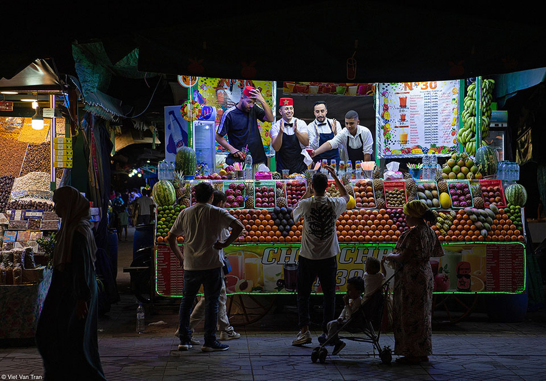 Những người bán hoa quả đêm tại chợ trung tâm ở phố cổ Marrakech đang chào đón khách đến mua hàng. Tác phẩm 