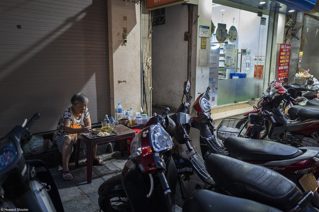 Tác phẩm "Vietnamese Woman finds calm and time to eat amongst the scooters" được tác giả Howard Shooter chụp trên đường phố Hà Nội nhộn nhịp. Bức ảnh đoạt giải nhì hạng mục Food at the Table