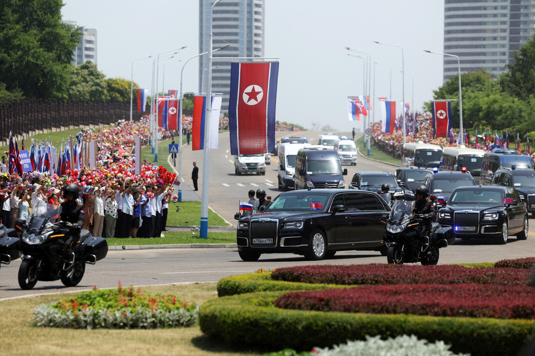 Đoàn xe hộ tống ông Putin từ sân bay Bình Nhưỡng về các địa điểm tiếp theo. Đường phố Bình Nhưỡng được trang trí khắp nơi bởi cờ hai nước, với người dân đổ ra đường đón ông Putin rất đông - Ảnh: SPUTNIK