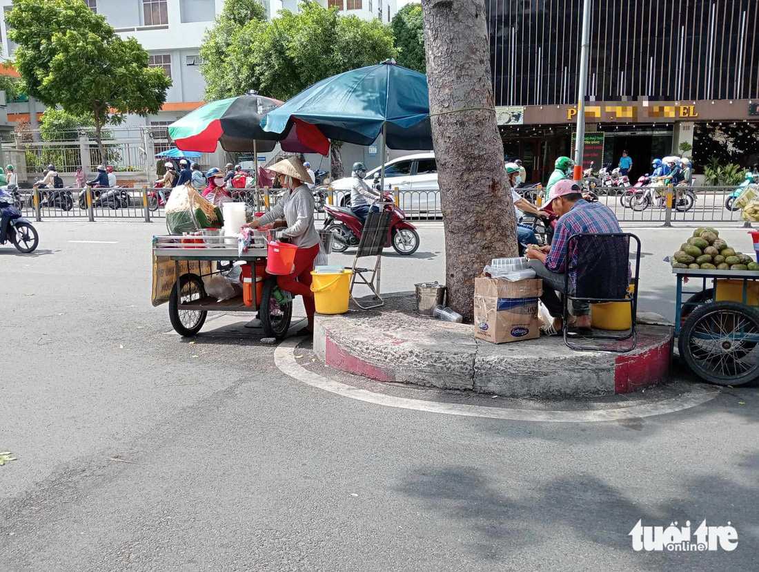 Nhiều người tận dụng khối bê tông vây kín gốc cây để buôn bán trên đường Ba Tháng Hai, quận 11 - Ảnh: ĐỊNH DƯƠNG