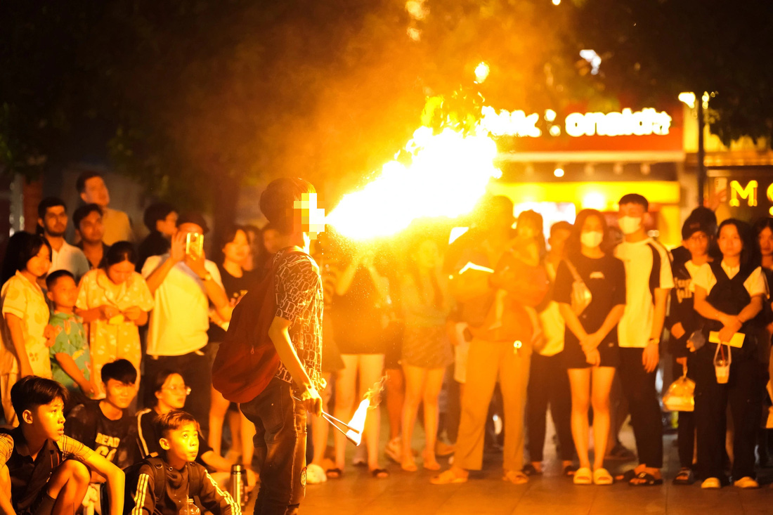 Nhiều người tập trung xem màn phun lửa của một nhóm trẻ trên phố đi bộ Nguyễn Huệ, quận 1 - Ảnh: DUY XUÂN