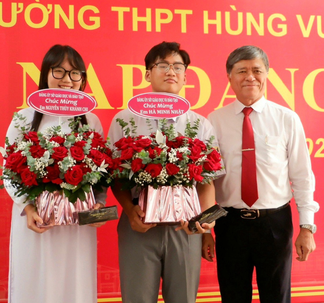 Ông Nguyễn Văn Hiếu, giám đốc Sở Giáo dục và Đào tạo TP.HCM, tặng hoa chúc mừng hai học sinh Hà Minh Nhật (giữa) và Nguyễn Thùy Khánh Chi - Ảnh: KIM ANH