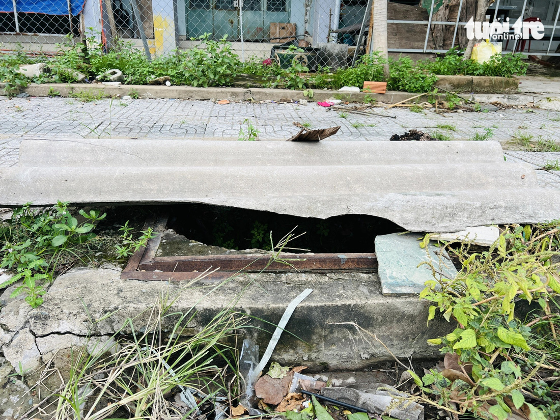 Nắp cống trên đường Nguyễn Quang Bật, TP Thủ Đức bị hư, người dân dùng tôn, nhánh cây che lại - Ảnh: XUÂN ĐOÀN