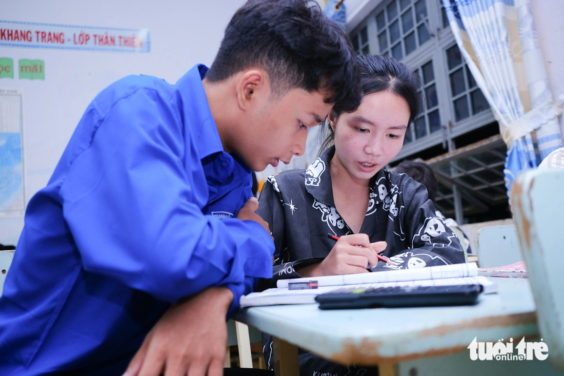 Em Dương Trúc Thư (phải), học sinh Trường THCS - THPT Kpă Klơng, huyện Mang Yang, ôn bài kèm cho bạn là em Sân, người Ba Na - Ảnh: TẤN LỰC 