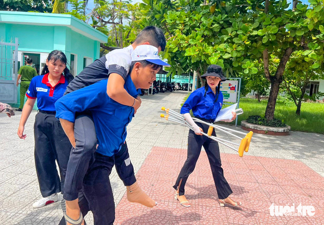Thí sinh Lê Võ Đình Duy, Trường THPT Quang Trung (Đà Nẵng), bị tai nạn khó di chuyển, nên các tình nguyện viên hỗ trợ dìu và cõng Duy vào phòng thi - Ảnh: ĐOÀN NHẠN