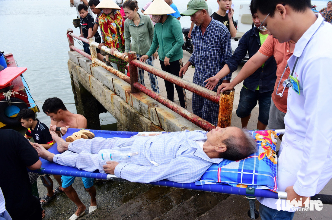 Bệnh nhân được y bác sĩ cùng người dân hỗ trợ đưa xuống ca nô để di chuyển vào đất liền