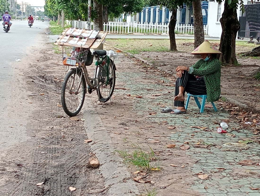 Bà Năm bán vé số thường xuyên ngủ ngồi trên đường Nguyễn Trãi, Dĩ An, Bình Dương - Ảnh: ĐỊNH DƯƠNG