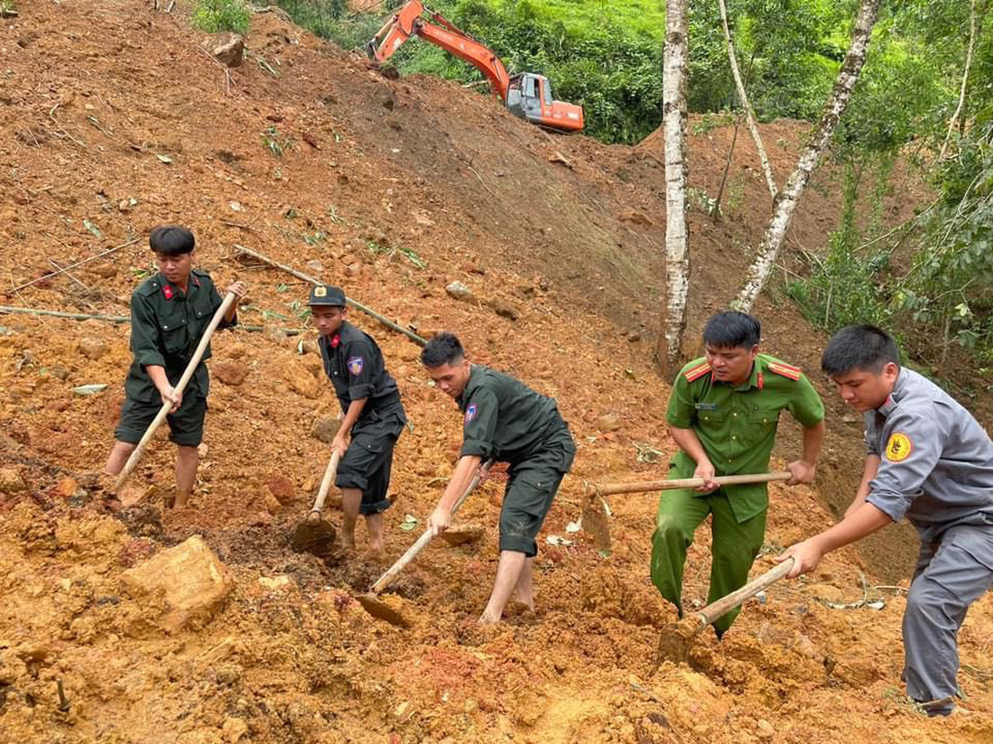 Cảnh sát dùng cuốc bới đất, dò tìm các nạn nhân mắc kẹt dưới bùn đất - Ảnh: Công an Hà Giang