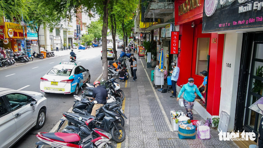 Vỉa hè được chia làm ba phần, phân biệt bằng màu sơn vạch kẻ. Phía ngoài cùng (sát đường giao thông) rộng khoảng 1m là chỗ để xe máy, chính giữa là lối dành cho người đi bộ khoảng 2m, còn phía trong cùng (sát mặt tiền nhà dân) là khu vực để cho hàng quán thuê làm mặt bằng kinh doanh, buôn bán - Ảnh: CHÂU TUẤN