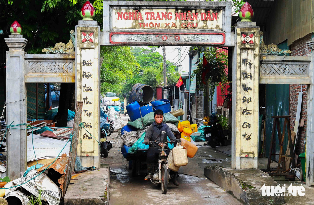 Một người đàn ông đang chở phế liệu từ nghĩa trang thôn Xà Cầu ra ngoài đường trục chính. Tại thôn Xà Cầu hiện có 170-180 hộ gia đình trên tổng số 800 hộ làm nghề thu mua, sơ chế rác thải nhựa - Ảnh: THÚY TRANG