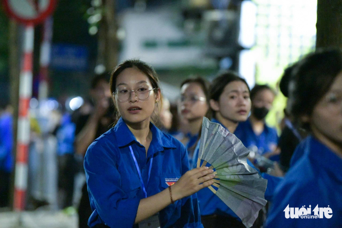 Mỗi người một chiếc quạt giấy, các bạn tình nguyện viên không ngơi tay quạt cho người dân đến viếng Tổng Bí thư - Ảnh: NAM TRẦN