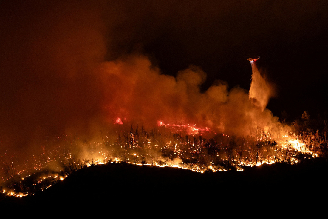 Một chiếc trực thăng thả nước xuống đám cháy rừng Thompson, khi lính cứu hỏa tiếp tục chiến đấu với đám cháy vào ban đêm gần thành phố Oroville, bang California, Mỹ ngày 2-7 - Ảnh: REUTERS