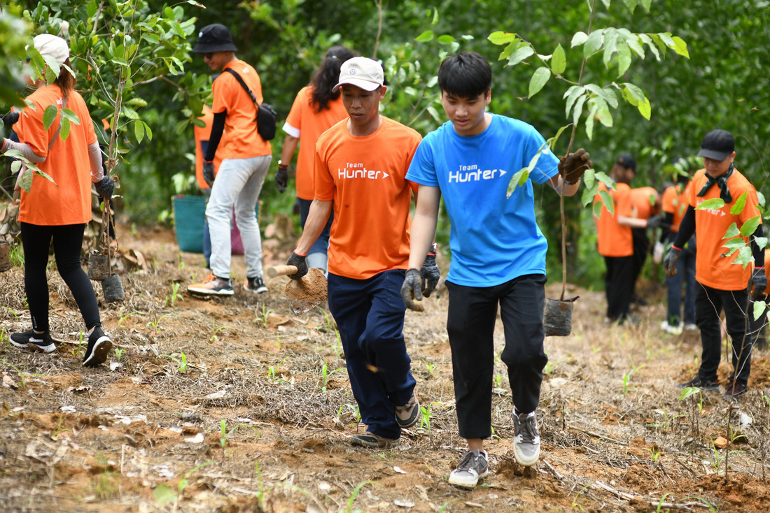Các tình nguyện viên Biti’s hăng hái mang những cây non chuẩn bị vun trồng - Ảnh: QUANG ĐỊNH