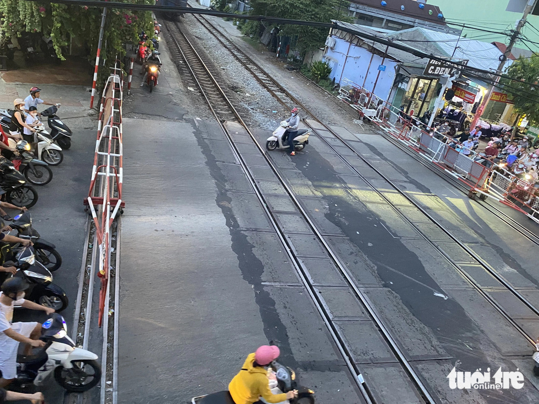 Cố gắng luồn vào bên trong gác chắn tàu để lát nữa đi "nhanh" hơn - Ảnh: TI NA