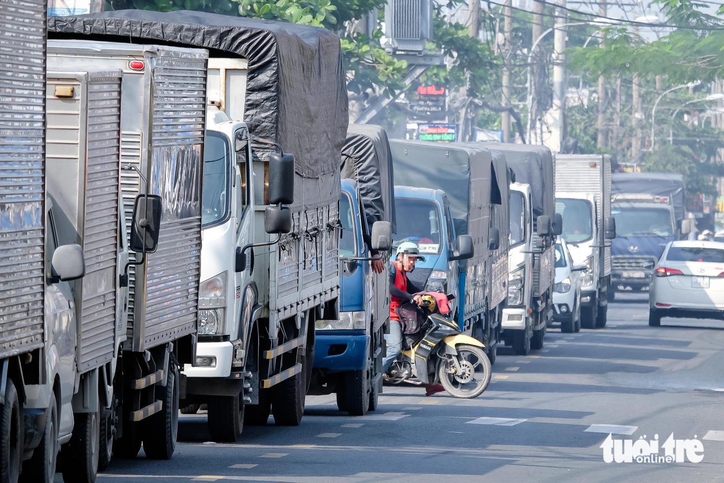 Kẹt xe trên đường Vĩnh Lộc hướng từ huyện Hóc Môn đi Bình Chánh, trưa 21-11. Một người điều khiển xe máy bất chấp nguy hiểm, len lỏi giữa hàng dài xe tải để chạy ngược chiều nhằm thoát khỏi dòng xe đang "đứng im"