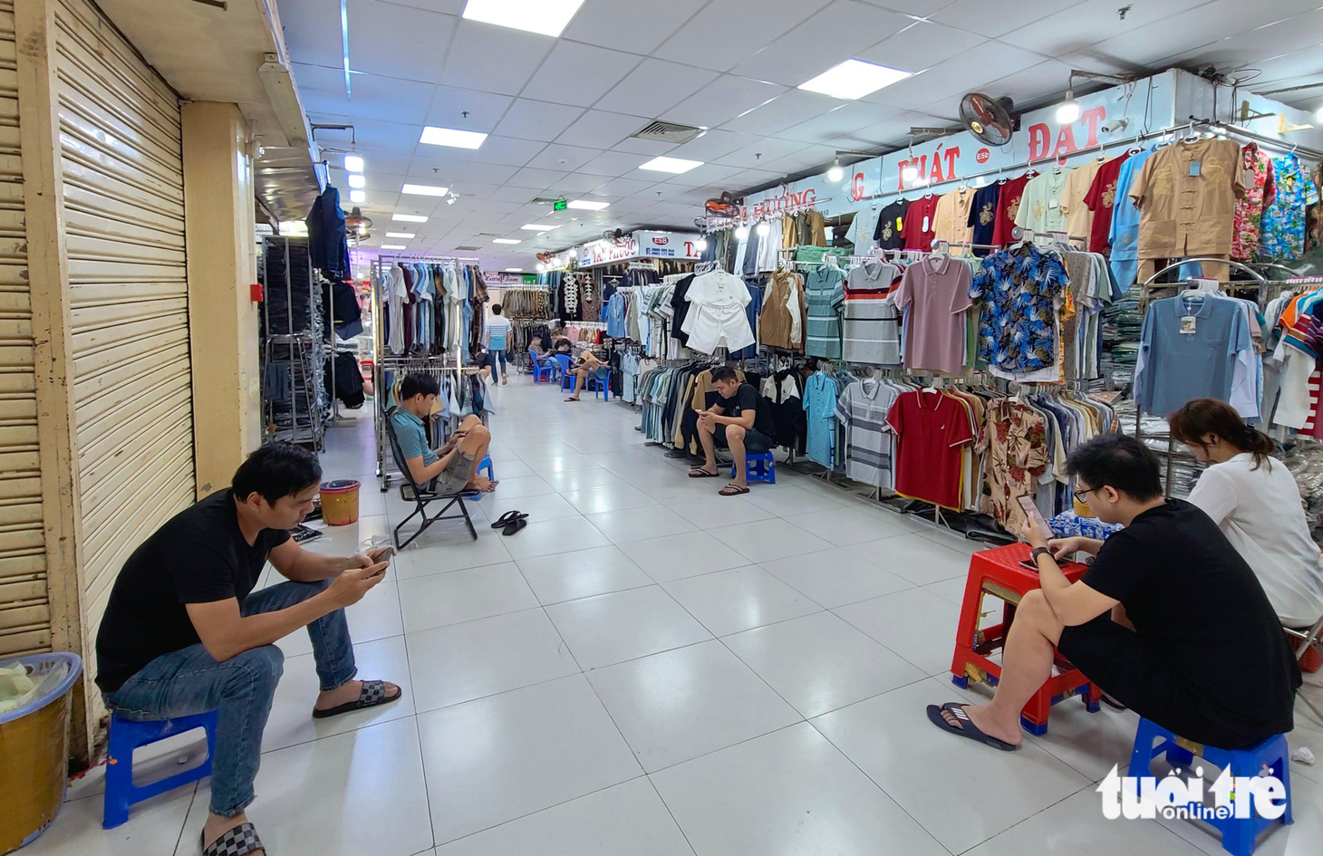 Không còn tràn ngập không khí khẩn trương đóng hàng như những năm trước dịch, tiểu thương chợ An Đông ngồi lướt điện thoại cả dãy - Ảnh: NHẬT XUÂN