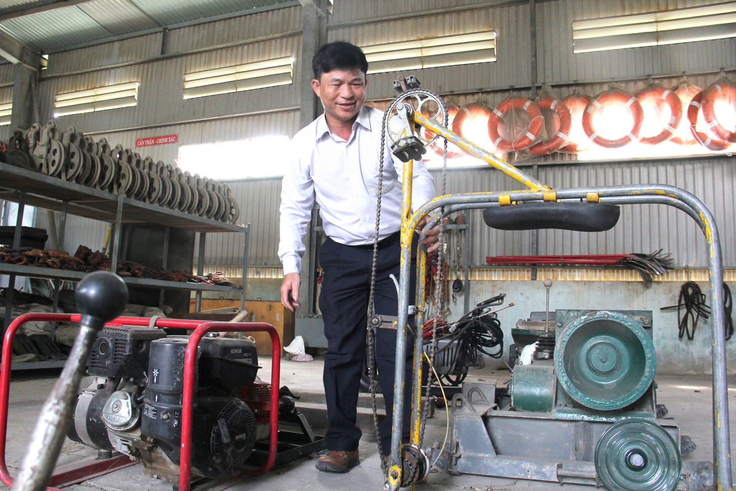 Ông Hiếu bên một chiếc xe đạp đi trên dây điện do mình sáng chế - Ảnh: TRẦN MAI
