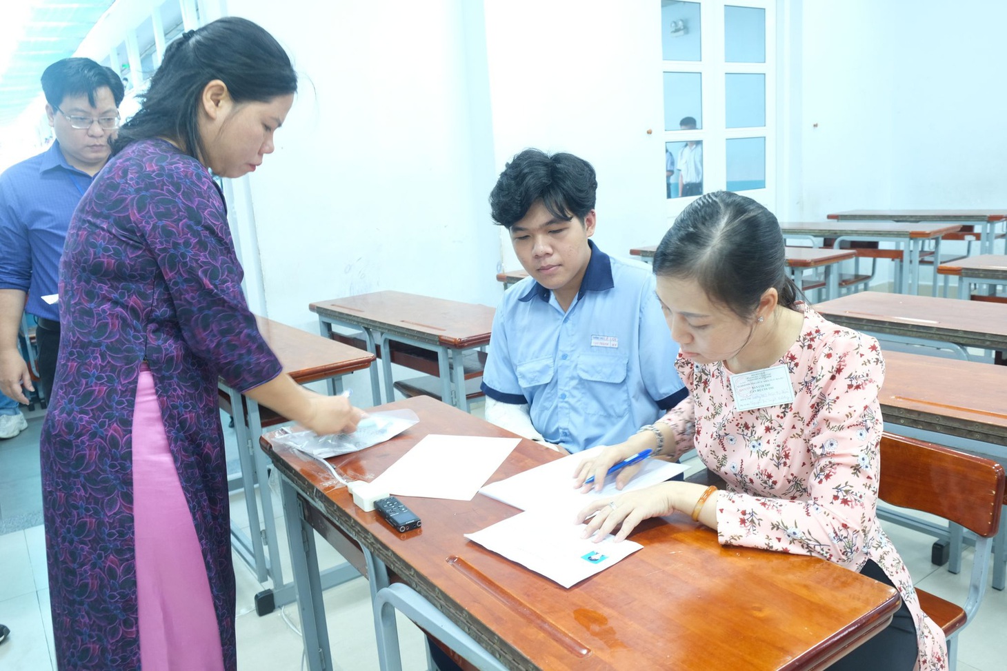 Em Nguyễn Vạn Thạnh (Trường THCS Lê Lợi) bị tai nạn phải bó tay, được cô Tuyết Hương viết hộ bài thi - Ảnh: NGỌC PHƯỢNG