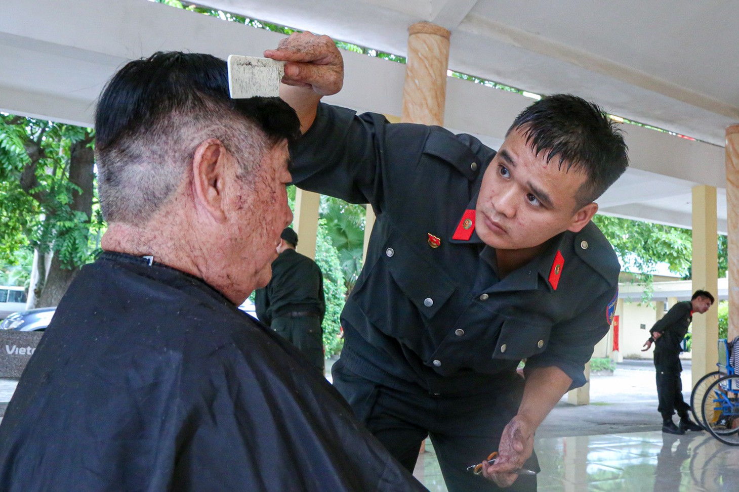 Trung úy cảnh sát cơ động Hoàng Anh mướt mồ hôi khi tạo kiểu cho các bác thương binh, vì sợ "cắt xấu các bác trừ điểm" - Ảnh: HÀ QUÂN