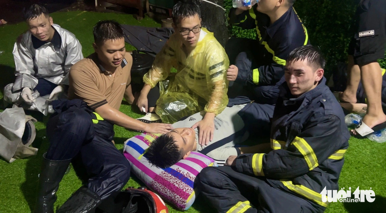 Một chiến sĩ kiệt sức nằm trên vỉa hè, được đồng đội chăm sóc - Ảnh: DANH TRỌNG