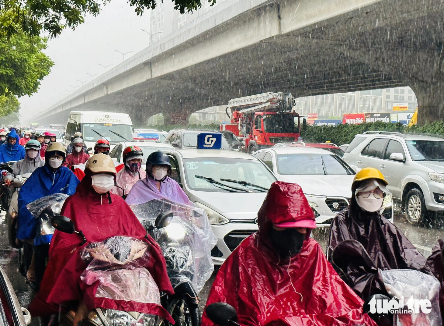Người Hà Nội đội mưa đi làm trong cơn mưa tầm tã - Ảnh: QUANG VIỄN