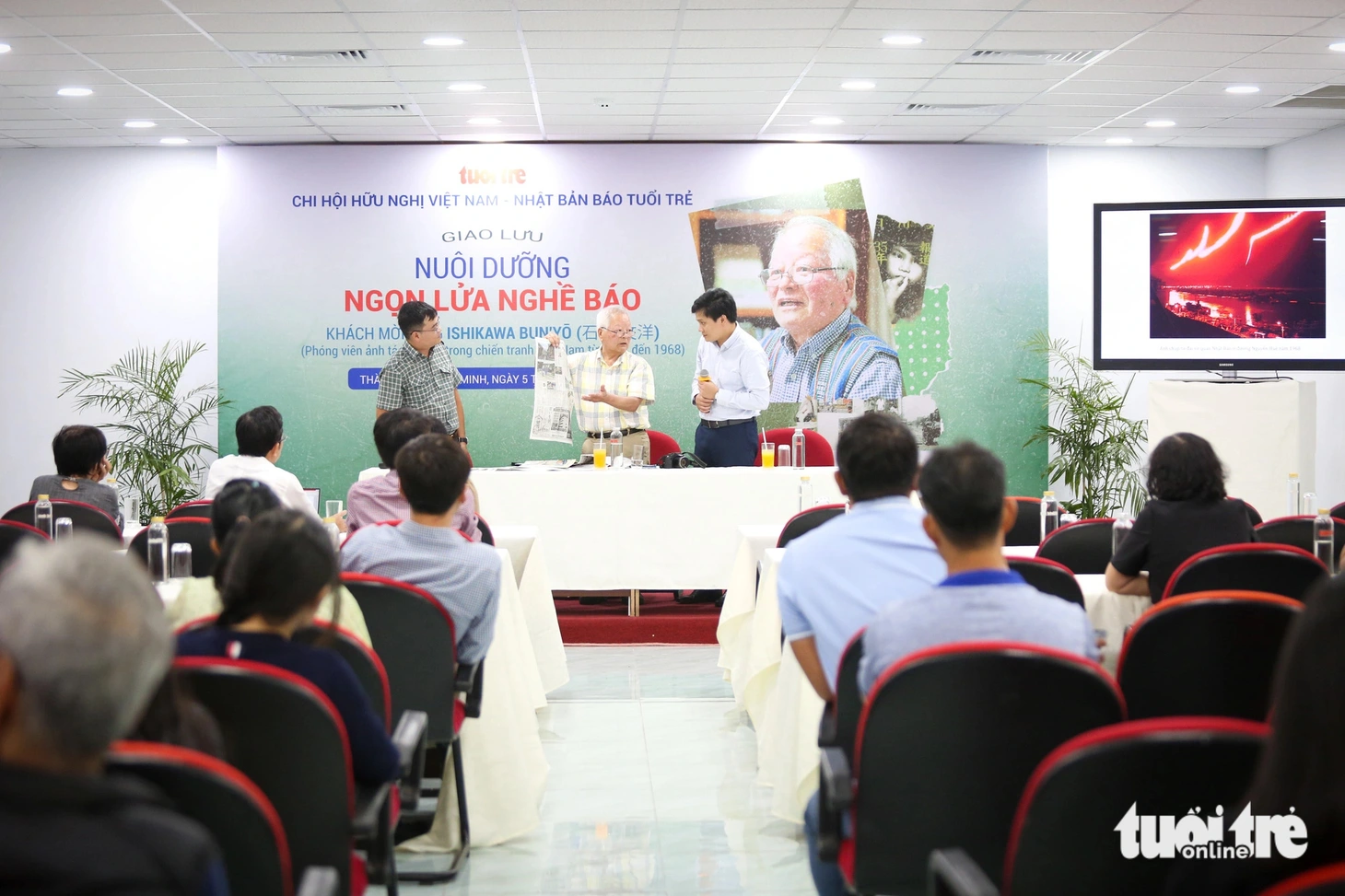 Ông Ishikawa giới thiệu trang báo có ảnh của mình chụp trận động đất ở Nhật Bản tháng 1-2024 - Ảnh: PHƯƠNG QUYÊN
