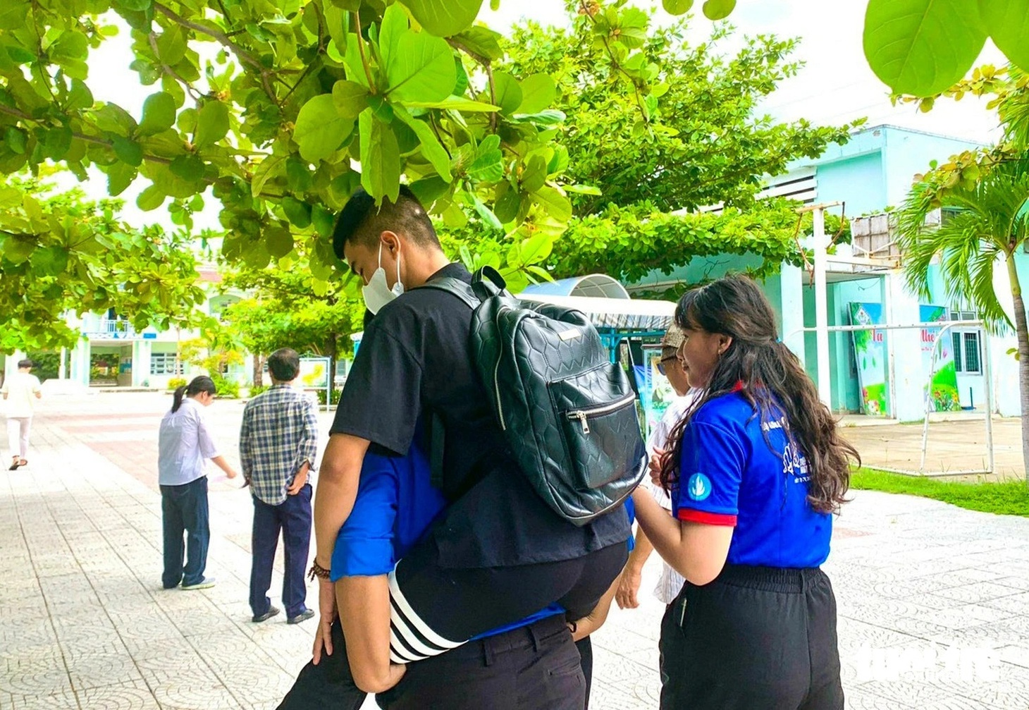 Tình nguyện viên Nguyễn Duy Thắng cõng bạn Duy là một thí sinh bị gãy chân phải bó bột vào phòng nghe quy chế thi chiều 26-6 - Ảnh: ĐOÀN NHẠN