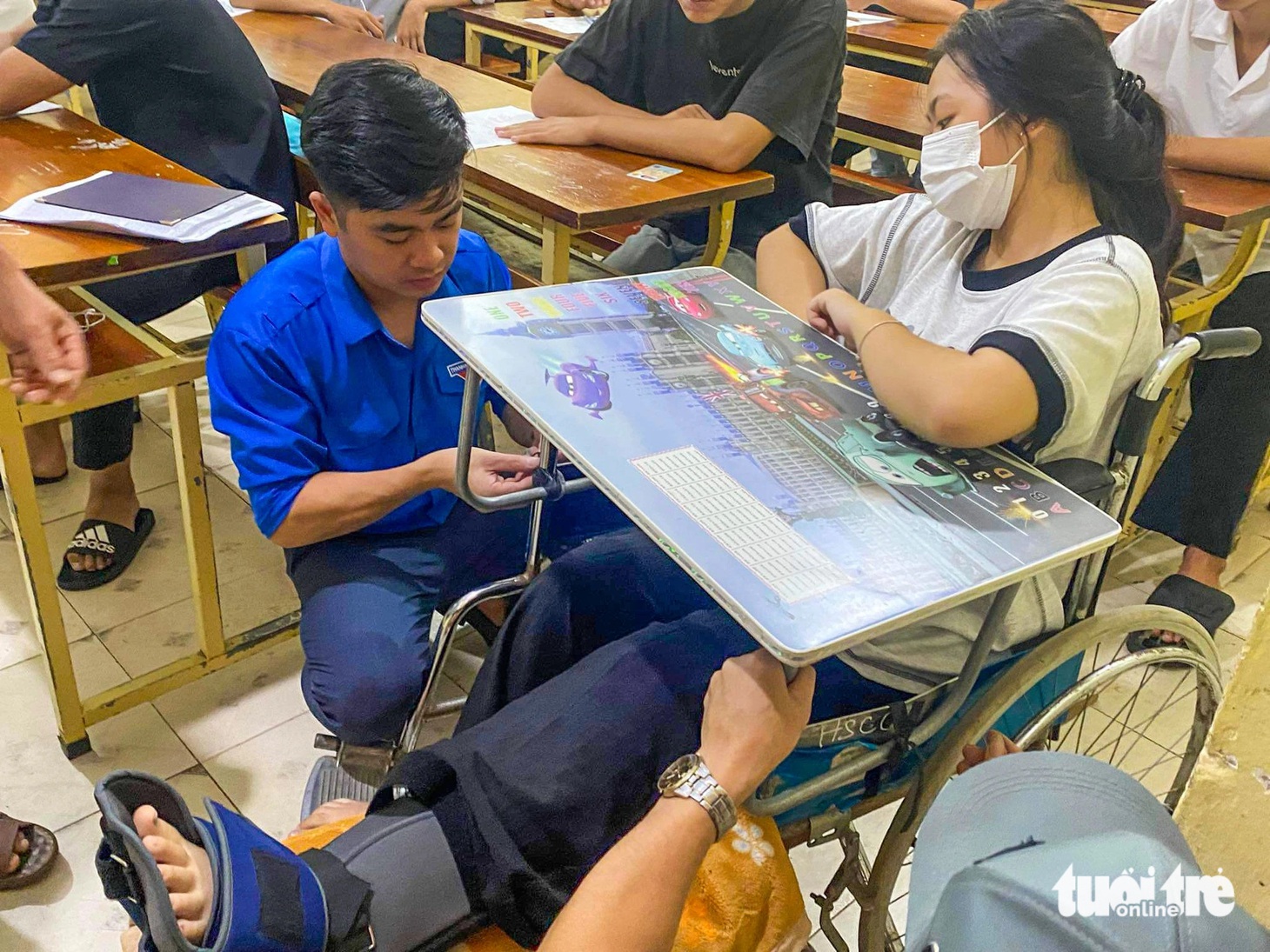 Thí sinh Trần Thị Linh Chi - bị tai nạn gãy chân trước ngày đi thi được anh chị tình nguyện viên huyện đoàn Đô Lương, Nghệ An hỗ trợ đưa vào phòng thi sáng 27-6 - Ảnh: SỸ TÍNH
