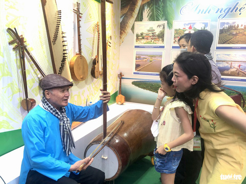 Nghệ nhân Võ Văn Bá giới thiệu chiếc đàn cò bằng gỗ dừa - Ảnh: HOÀI PHƯƠNG