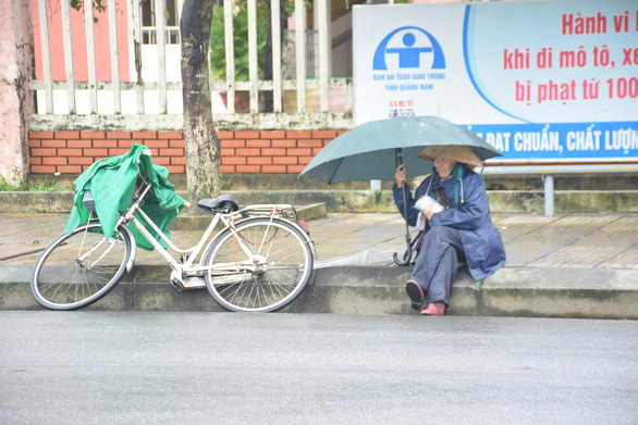 Những người già bán vé số đội mưa, co ro trong giá rét để mưu sinh - Ảnh 1.