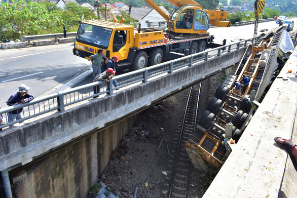 Xe đầu kéo húc văng cầu vượt, rơi ngửa trên đường sắt, cả tấn quýt tết văng vãi - Ảnh 1.