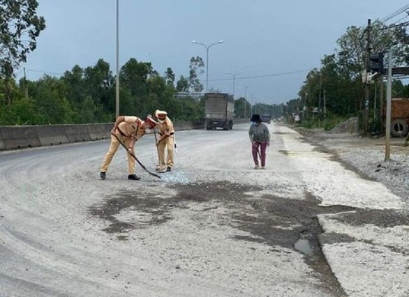 Cảnh sát giao thông dùng chổi, xẻng dọn dẹp đá dăm trên quốc lộ - Ảnh 1. Cảnh sát giao thông dùng chổi, xẻng dọn dẹp đá dăm trên quốc lộ - Ảnh 1.