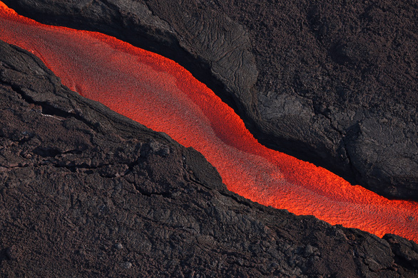 Dung nham chảy ra từ khe nứt của núi lửa Mauna Loa khi ngọn núi lửa này phun trào vào ngày 5-12-2022 tại Hilo, Hawaii.  Đây là lần đầu tiên sau gần 40 năm, núi lửa Mauna Loa, ngọn núi lửa đang hoạt động lớn nhất thế giới, phun trào - Ảnh:  AFP