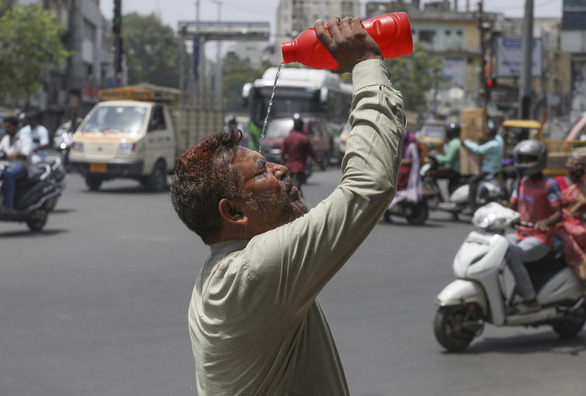 Ấn Độ dùng xe phun nước vào người đi đường để hạ nhiệt trong đợt nắng nóng kỷ lục - Ảnh 2.