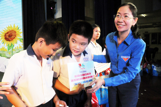 Chị Phan Thị Thanh Phương (bí thư Thành Đoàn) trao học bổng và dụng cụ học tập cho các bạn nhỏ bị ảnh hưởng bởi dịch covid-19 - Ảnh: NVCC