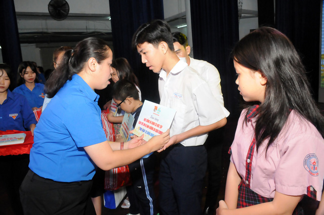 Chị Trịnh Thị Hiền Trân (chủ tịch Hội đồng Đội TP.HCM ) trao tặng kinh phí hỗ trợ và dụng cụ học tập cho các bạn nhỏ. - Ảnh: NVCC