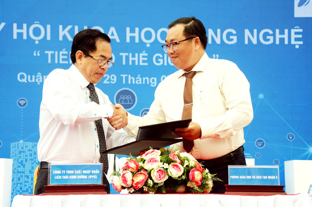 Thầy Phạm Đặng Khoa (Trưởng phòng GD & ĐT quận 3, bìa phải) trao bảng kí kết hợp tác với ông Vũ Ngọc Sơn (đại diện công ty TNHH XNK Liên Thái Bình Dương thuộc tập đoàn IPP Group) Ảnh: Nguyễn Hưng