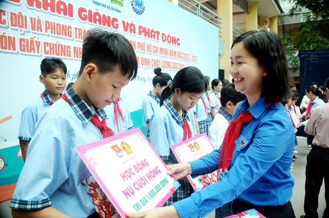 Chị Phạm Thị Thảo Linh trao học bổng Nụ cười hồng cho các bạn đội viên - Ảnh: NGUYỄN HƯNG
