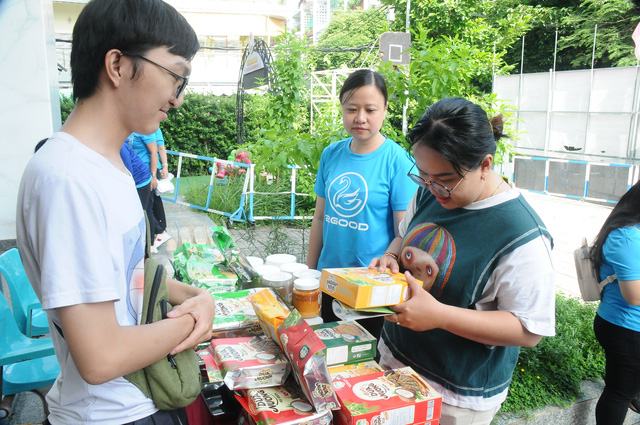 Các bậc phụ huynh và học sinh cùng tìm hiểu sản phẩm hộp giấy thân thiện với môi trường - Ảnh: NGUYỄN HƯNG