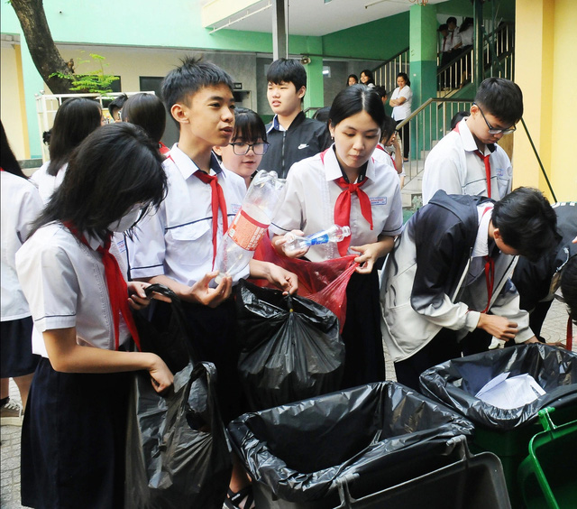 Học sinh Trường THCS Đồng Khởi mang rác đến đổi chậu cây xanh - Ảnh: NGUYỄN HƯNG