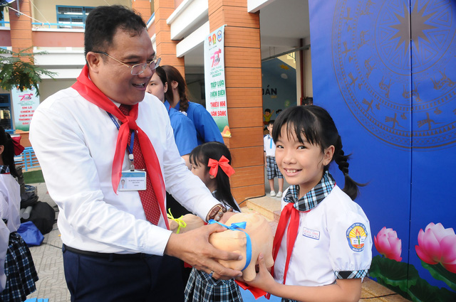 Thầy hiệu trưởng Dương Trần Bình trao heo đất cho các bạn đội viên. Ảnh: NGUYỄN HƯNG